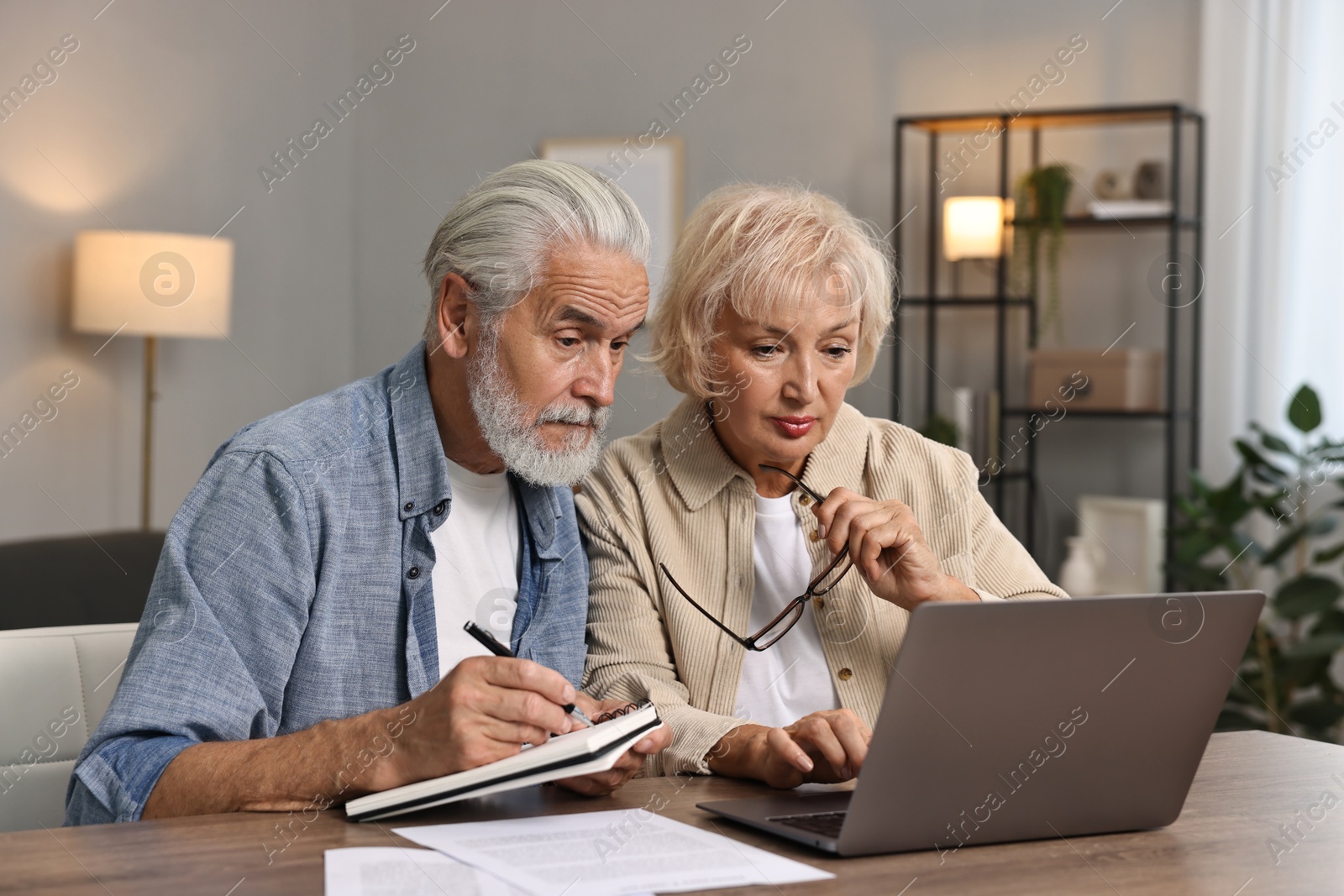 Photo of Pension savings. Senior couple planning budget at wooden table indoors