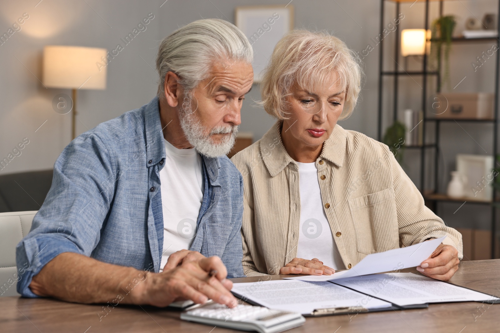 Photo of Pension savings. Senior couple planning budget at wooden table indoors