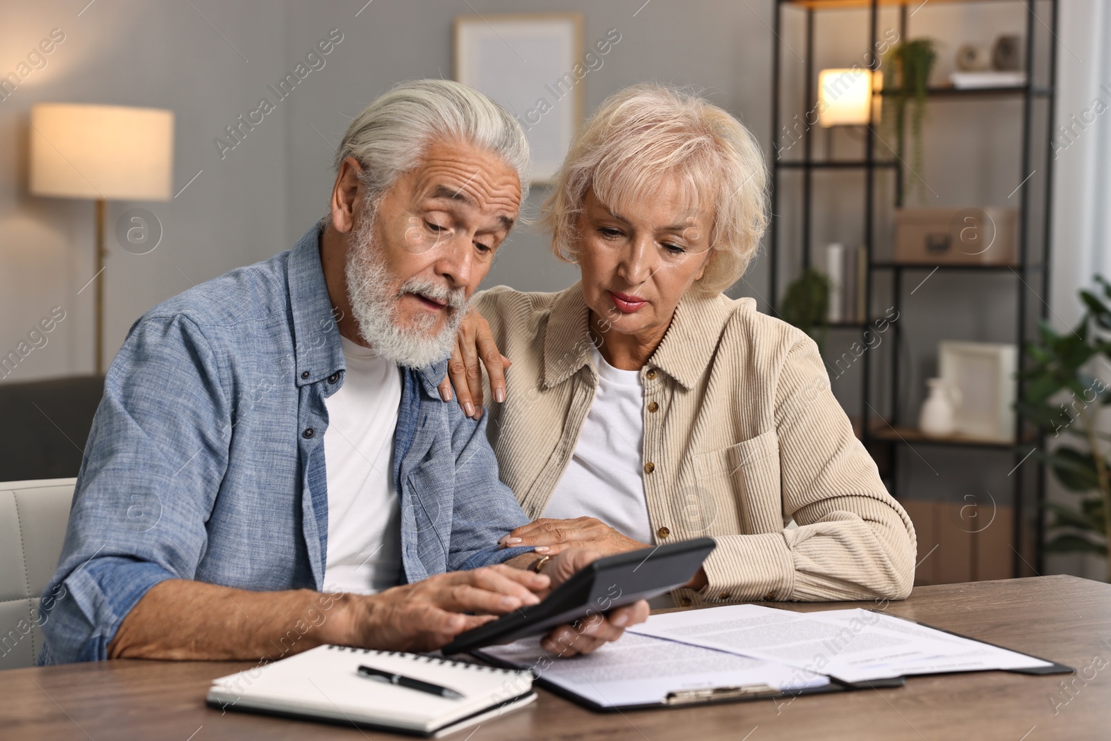 Photo of Pension savings. Senior couple planning budget at wooden table indoors