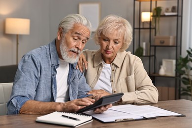 Pension savings. Senior couple planning budget at wooden table indoors