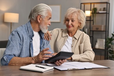 Pension savings. Senior couple planning budget at wooden table indoors