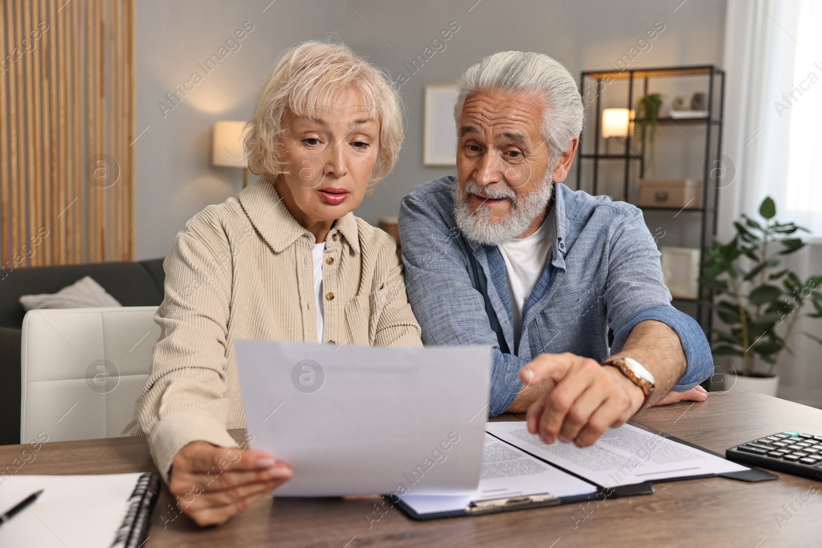 Photo of Pension savings. Senior couple planning budget at wooden table indoors