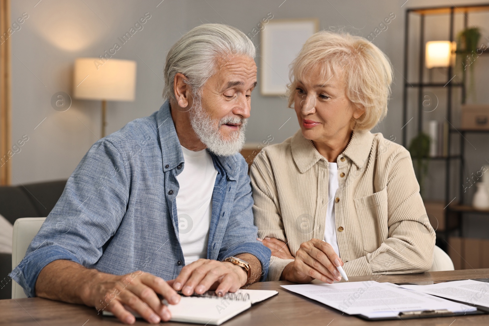 Photo of Pension savings. Senior couple planning budget at wooden table indoors