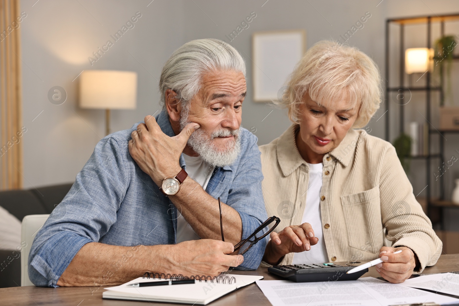 Photo of Pension savings. Senior couple planning budget at wooden table indoors