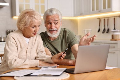 Photo of Pension savings. Senior couple planning budget at wooden table indoors