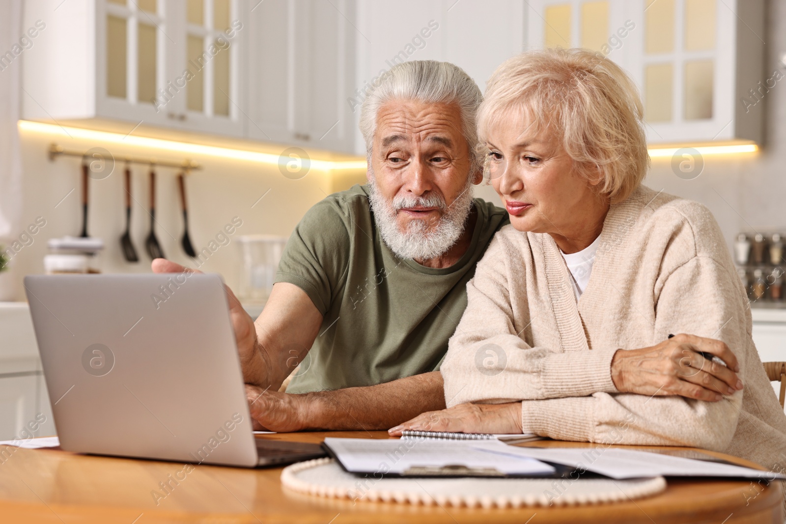 Photo of Pension savings. Senior couple planning budget at wooden table indoors