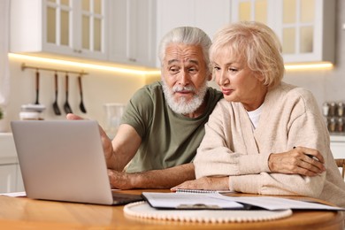 Photo of Pension savings. Senior couple planning budget at wooden table indoors