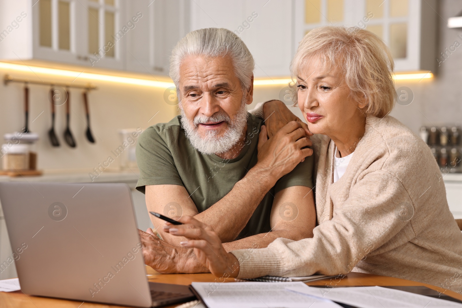 Photo of Pension savings. Senior couple planning budget at wooden table indoors