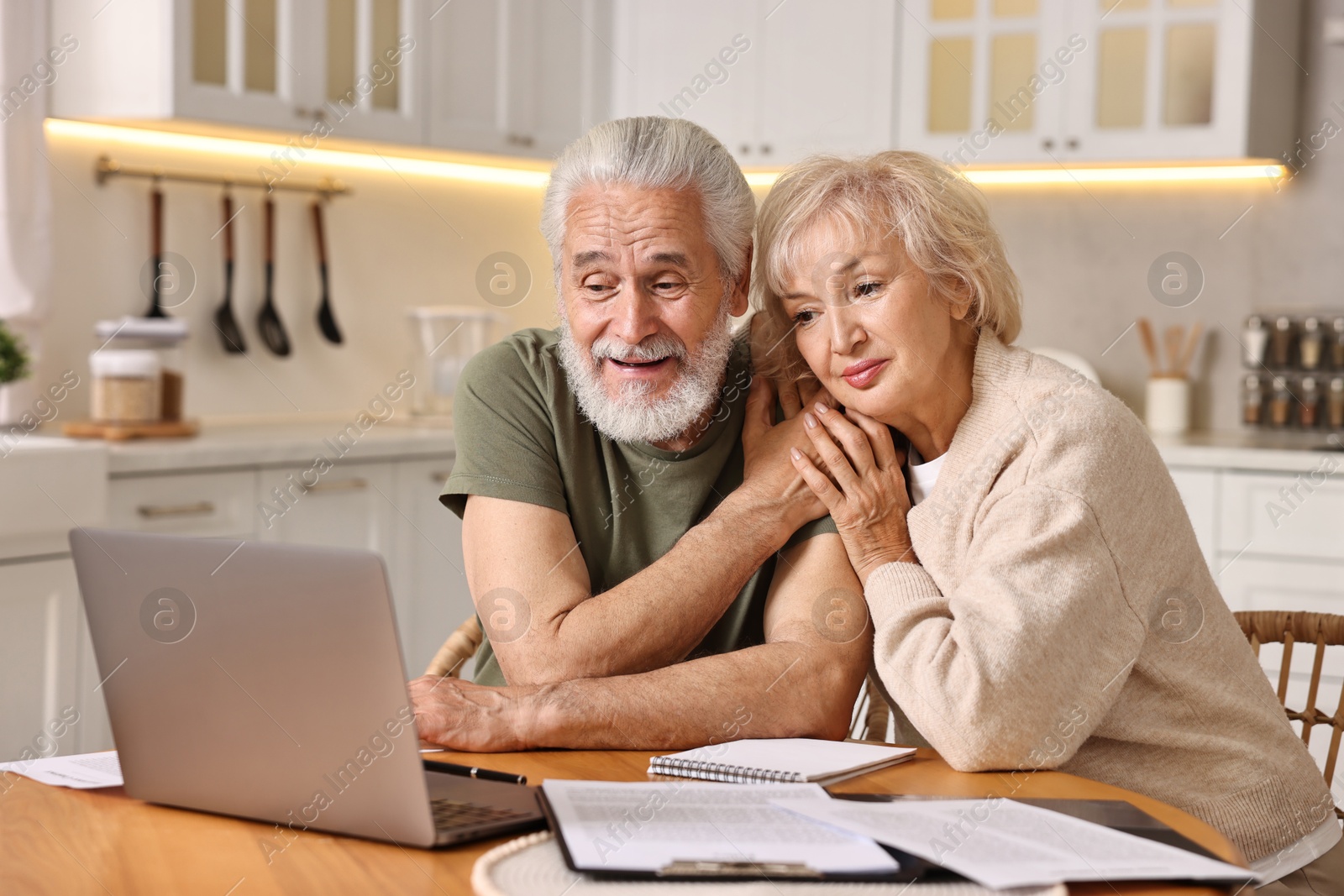 Photo of Pension savings. Senior couple planning budget at wooden table indoors