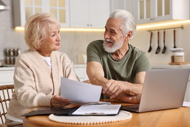 Pension savings. Senior couple planning budget at wooden table indoors