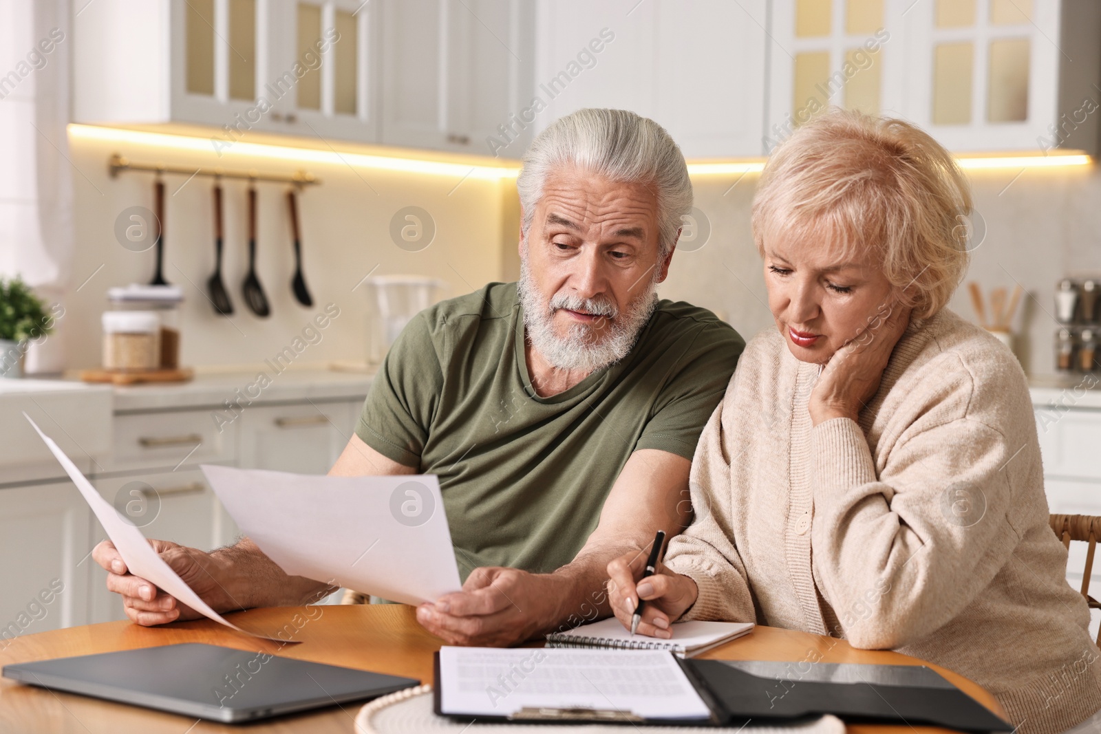 Photo of Pension savings. Senior couple planning budget at wooden table indoors