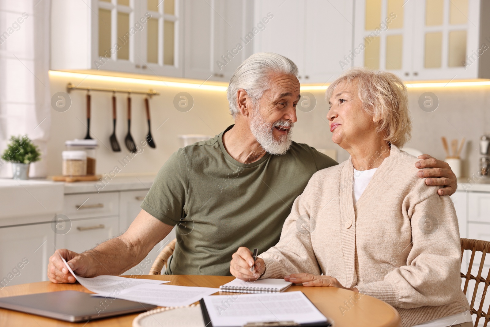 Photo of Pension savings. Senior couple planning budget at wooden table indoors