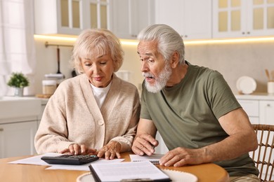 Photo of Pension savings. Senior couple planning budget at wooden table indoors