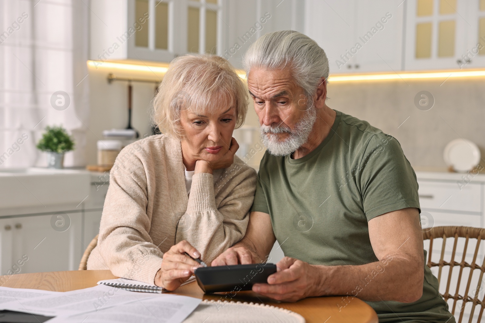 Photo of Pension savings. Senior couple planning budget at wooden table indoors