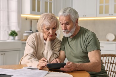 Photo of Pension savings. Senior couple planning budget at wooden table indoors