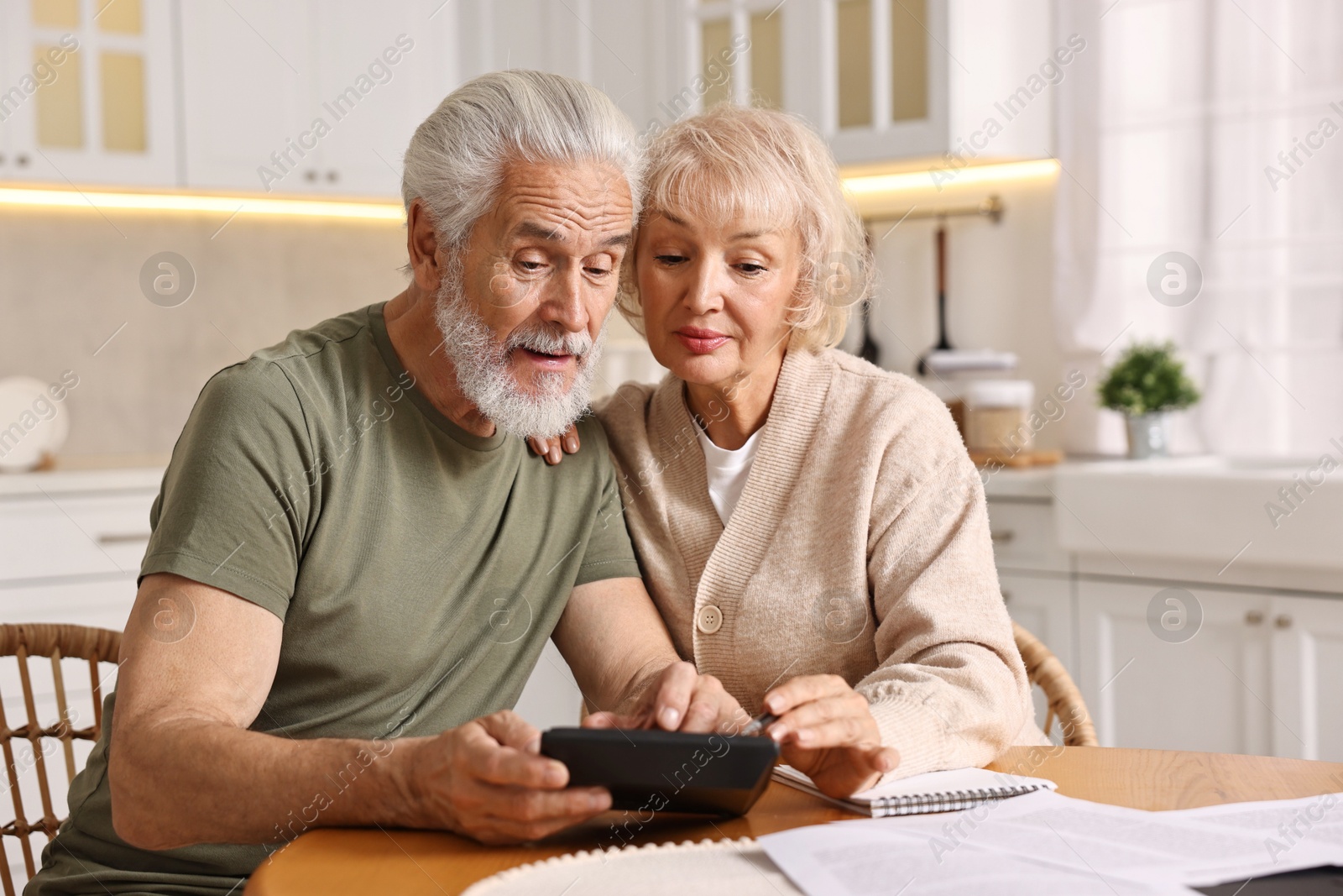 Photo of Pension savings. Senior couple planning budget at wooden table indoors