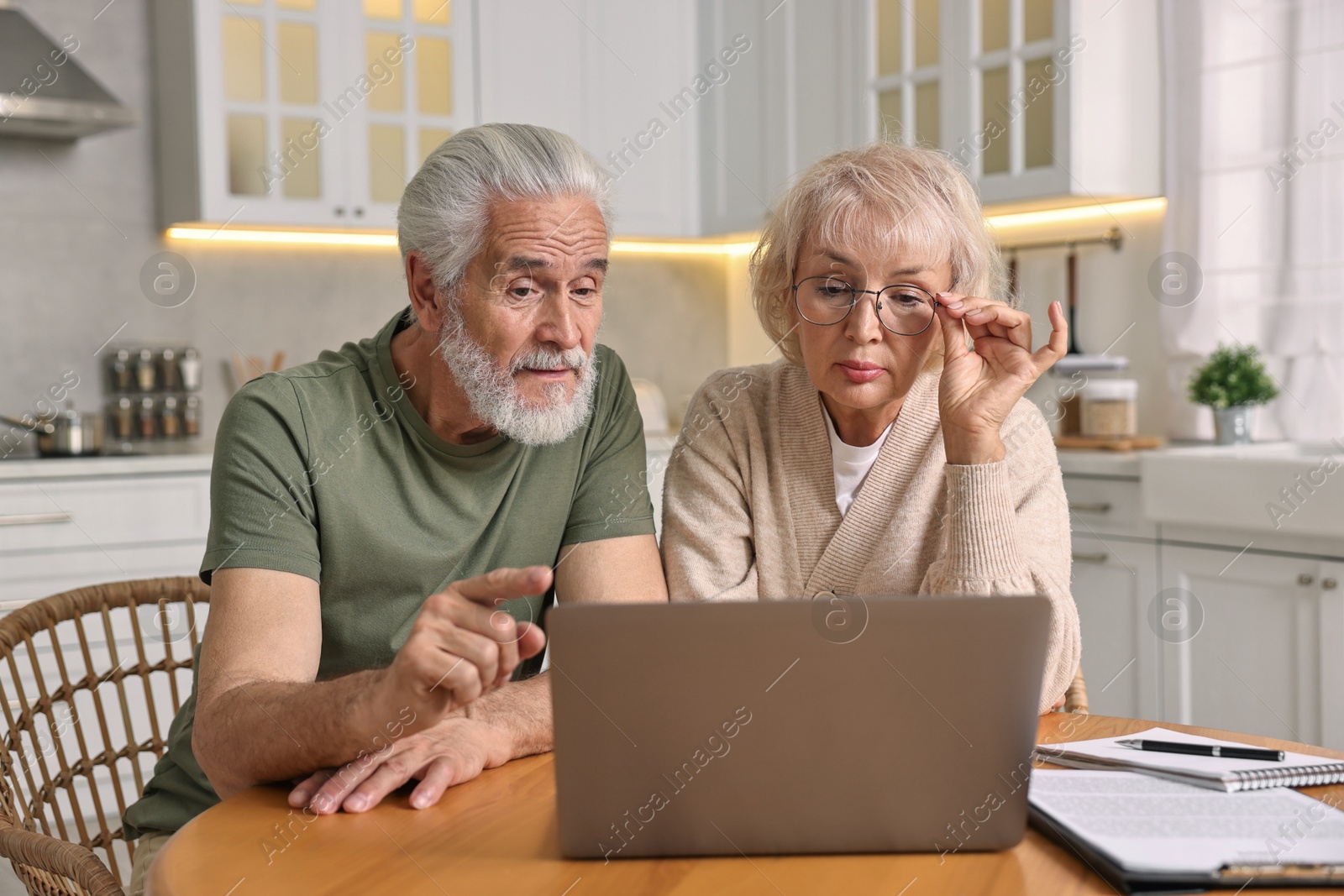 Photo of Pension savings. Senior couple planning budget at wooden table indoors