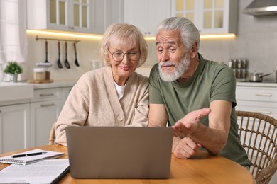 Pension savings. Senior couple planning budget at wooden table indoors