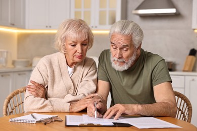 Photo of Pension savings. Senior couple planning budget at wooden table indoors