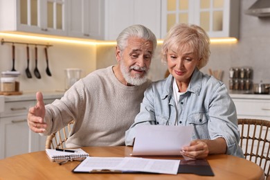 Pension savings. Senior couple planning budget at wooden table indoors