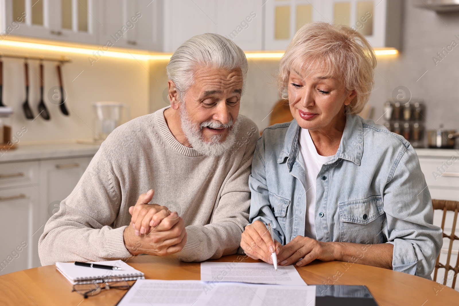 Photo of Pension savings. Senior couple planning budget at wooden table indoors