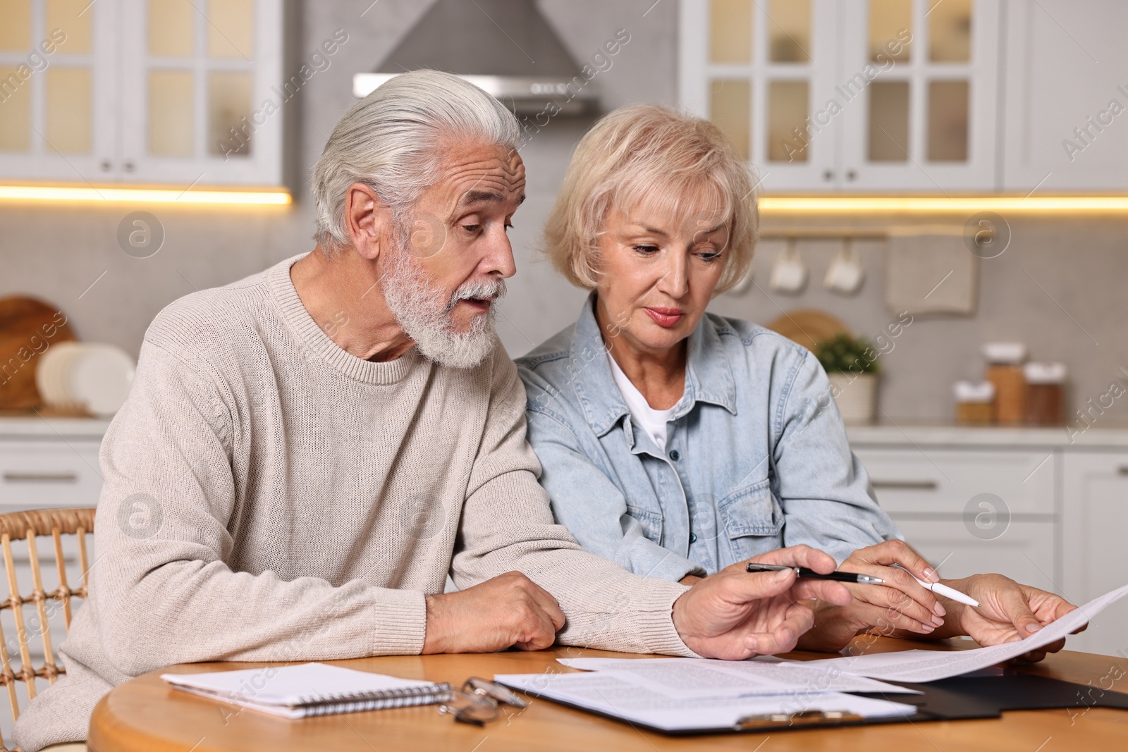 Photo of Pension savings. Senior couple planning budget at wooden table indoors