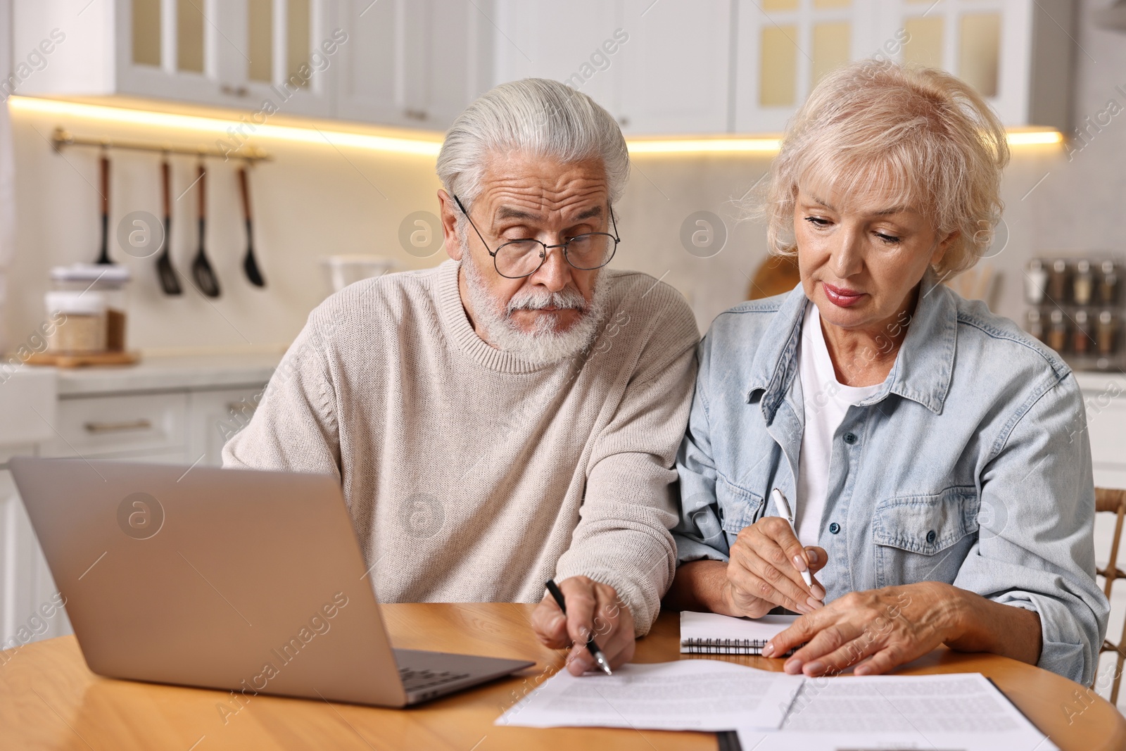 Photo of Pension savings. Senior couple planning budget at wooden table indoors