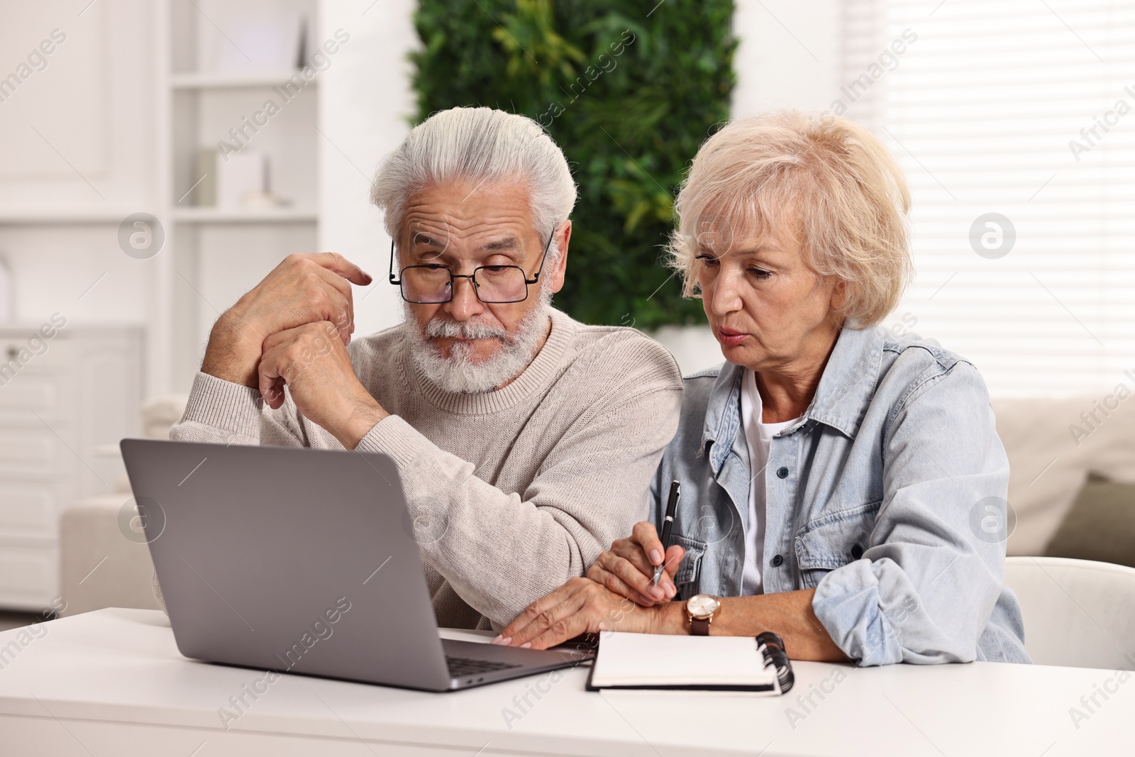 Photo of Pension savings. Senior couple planning budget at white table indoors