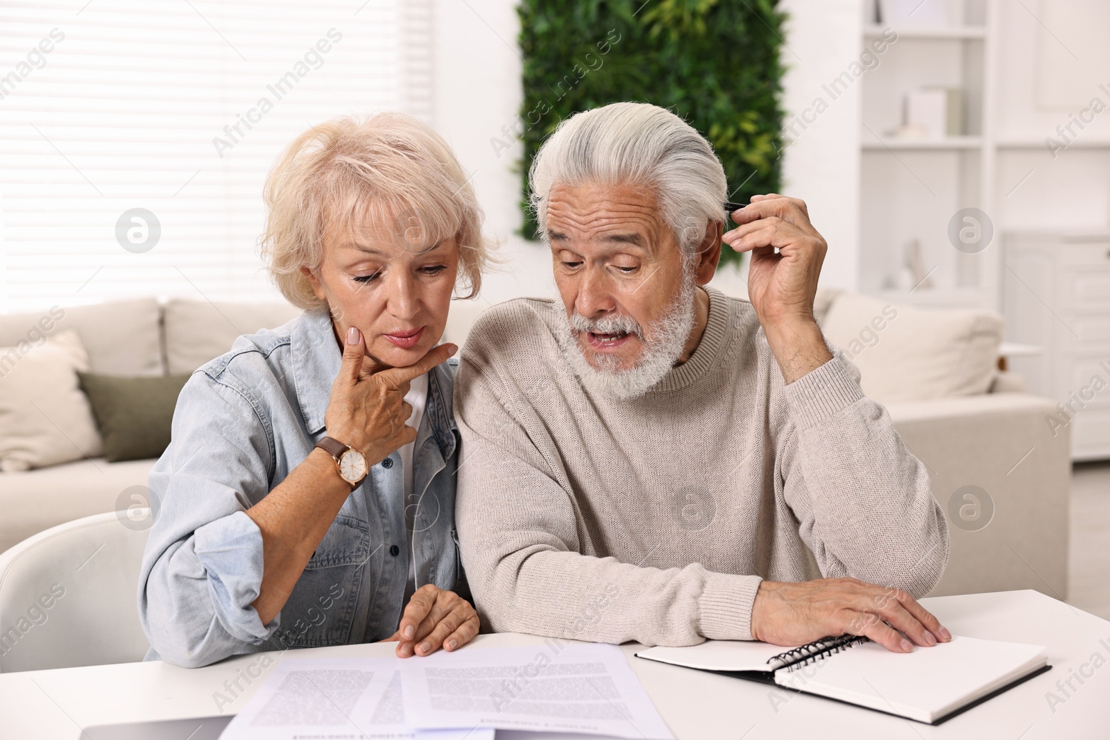 Photo of Pension savings. Senior couple planning budget at white table indoors