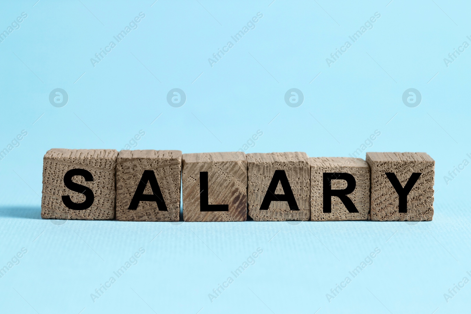 Photo of Word Salary made of cubes on light blue background