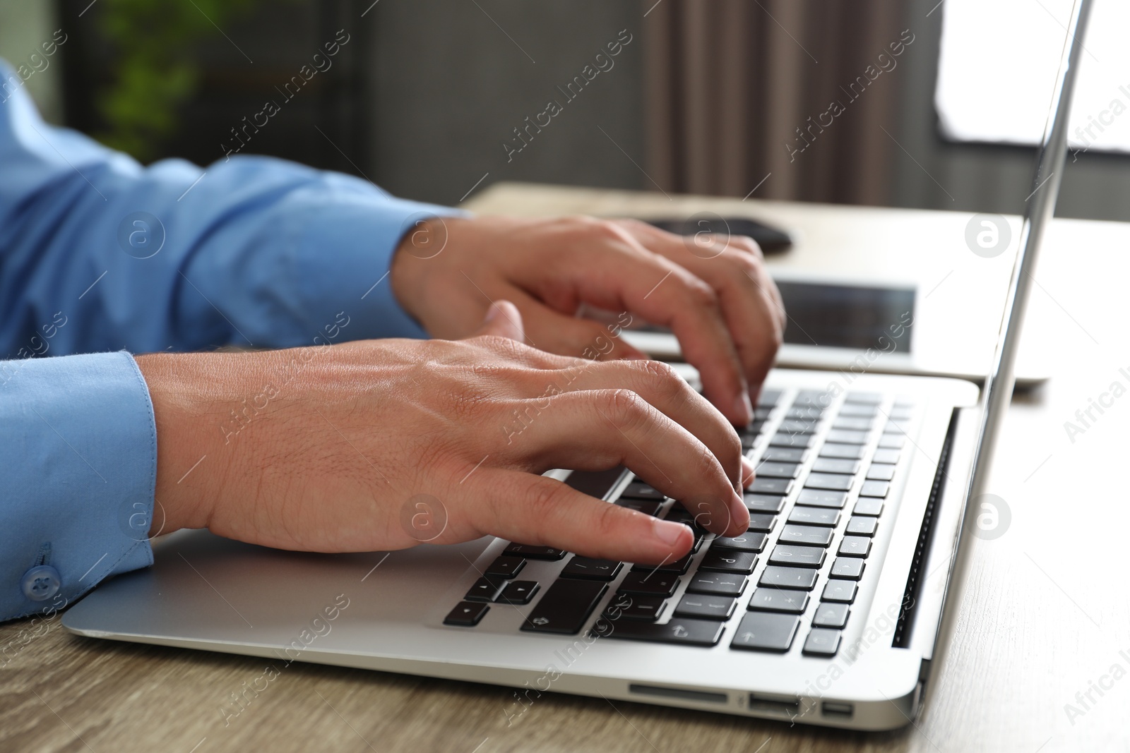 Photo of Businessman using laptop at wooden table, closeup. Modern technology