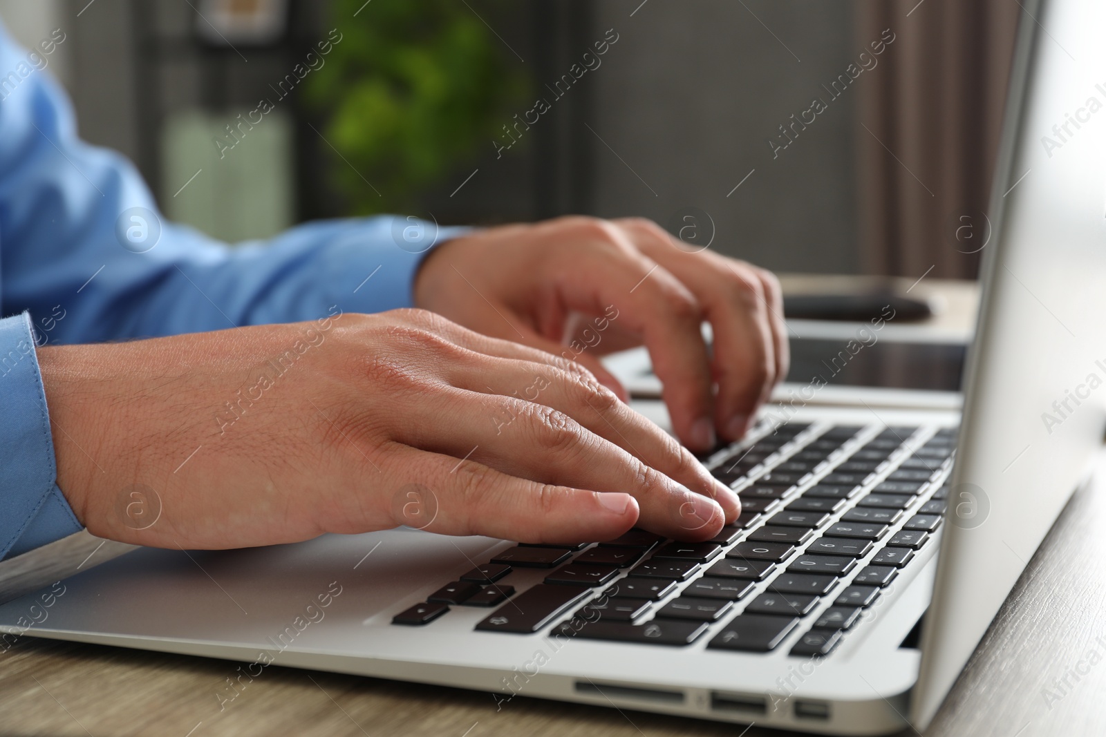 Photo of Businessman using laptop at wooden table, closeup. Modern technology