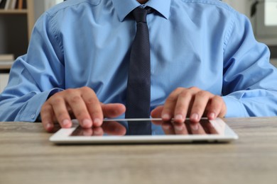 Photo of Businessman with tablet at wooden table, closeup. Modern technology