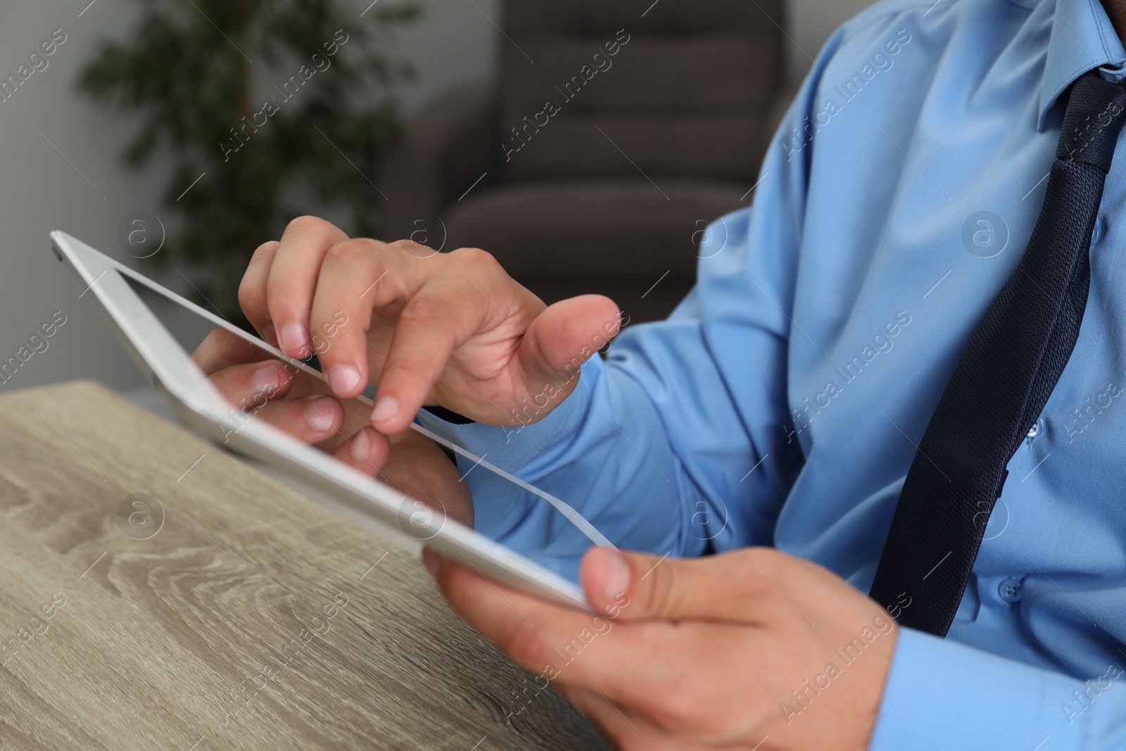 Photo of Businessman with tablet at wooden table, closeup. Modern technology