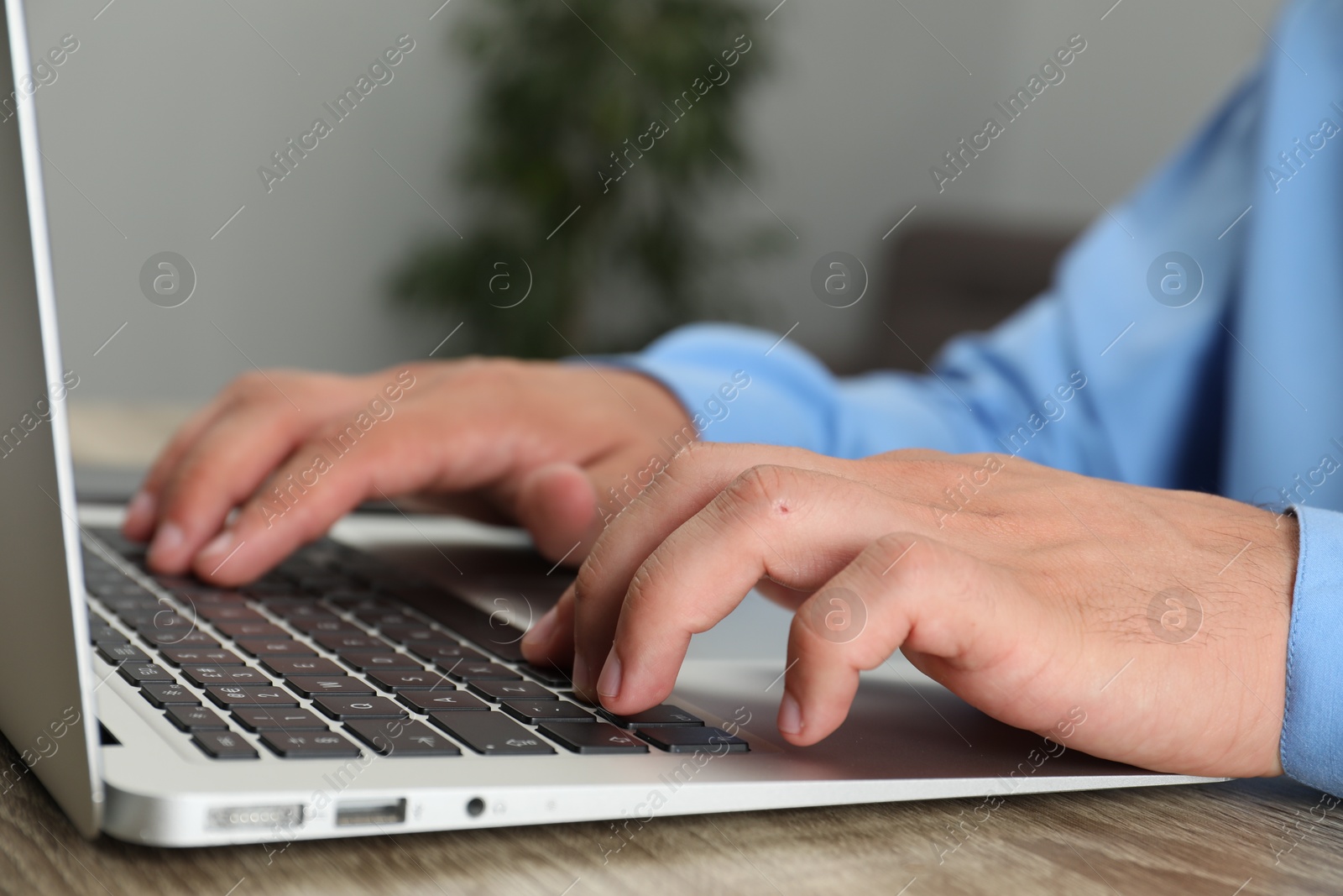 Photo of Businessman using laptop at wooden table, closeup. Modern technology