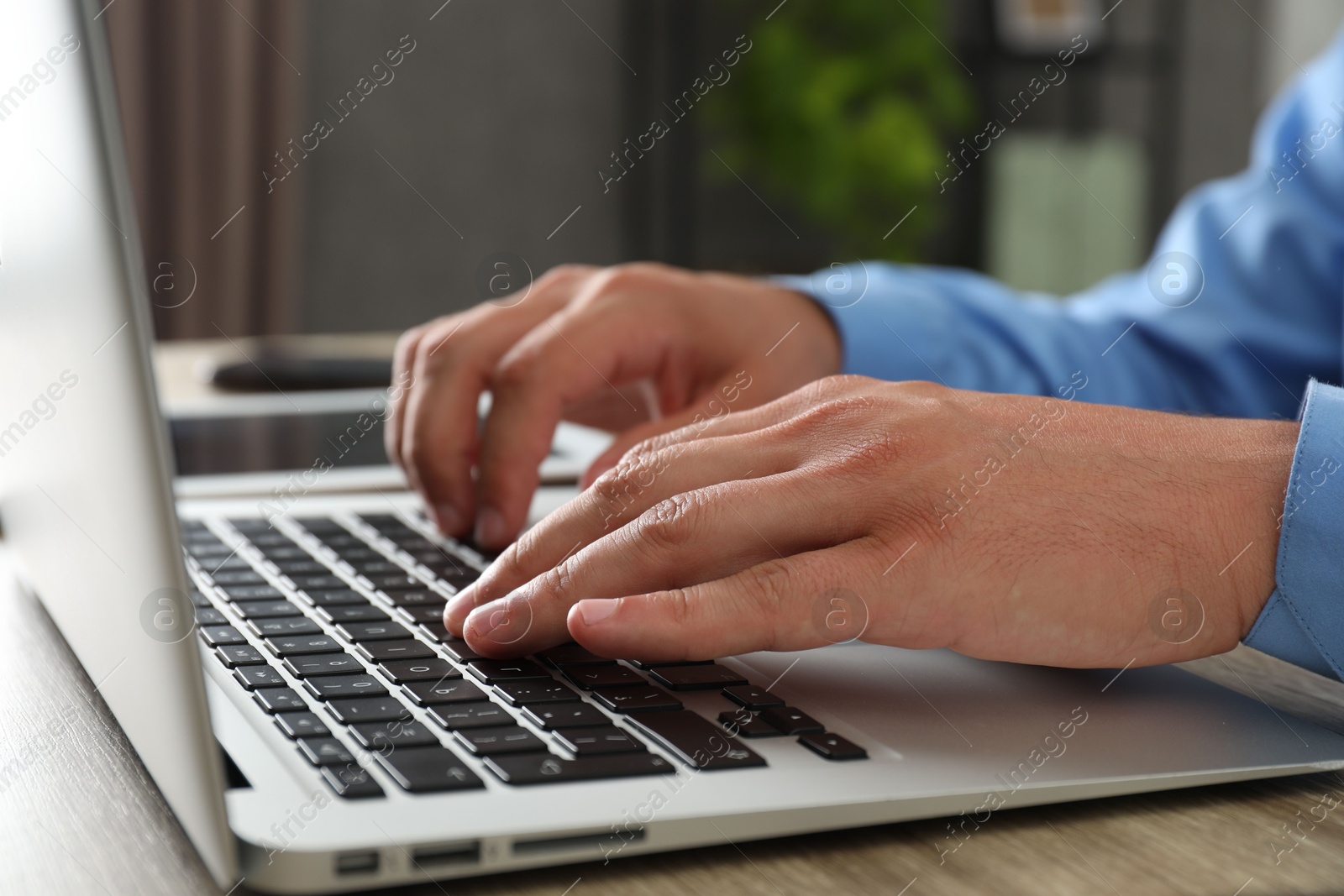 Photo of Businessman using laptop at wooden table, closeup. Modern technology