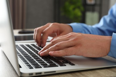 Photo of Businessman using laptop at wooden table, closeup. Modern technology