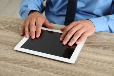 Photo of Businessman using tablet at wooden table, closeup. Modern technology