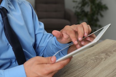 Photo of Businessman using tablet at wooden table, closeup. Modern technology