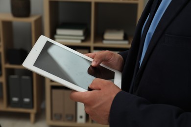 Photo of Businessman using tablet in office, closeup. Modern technology