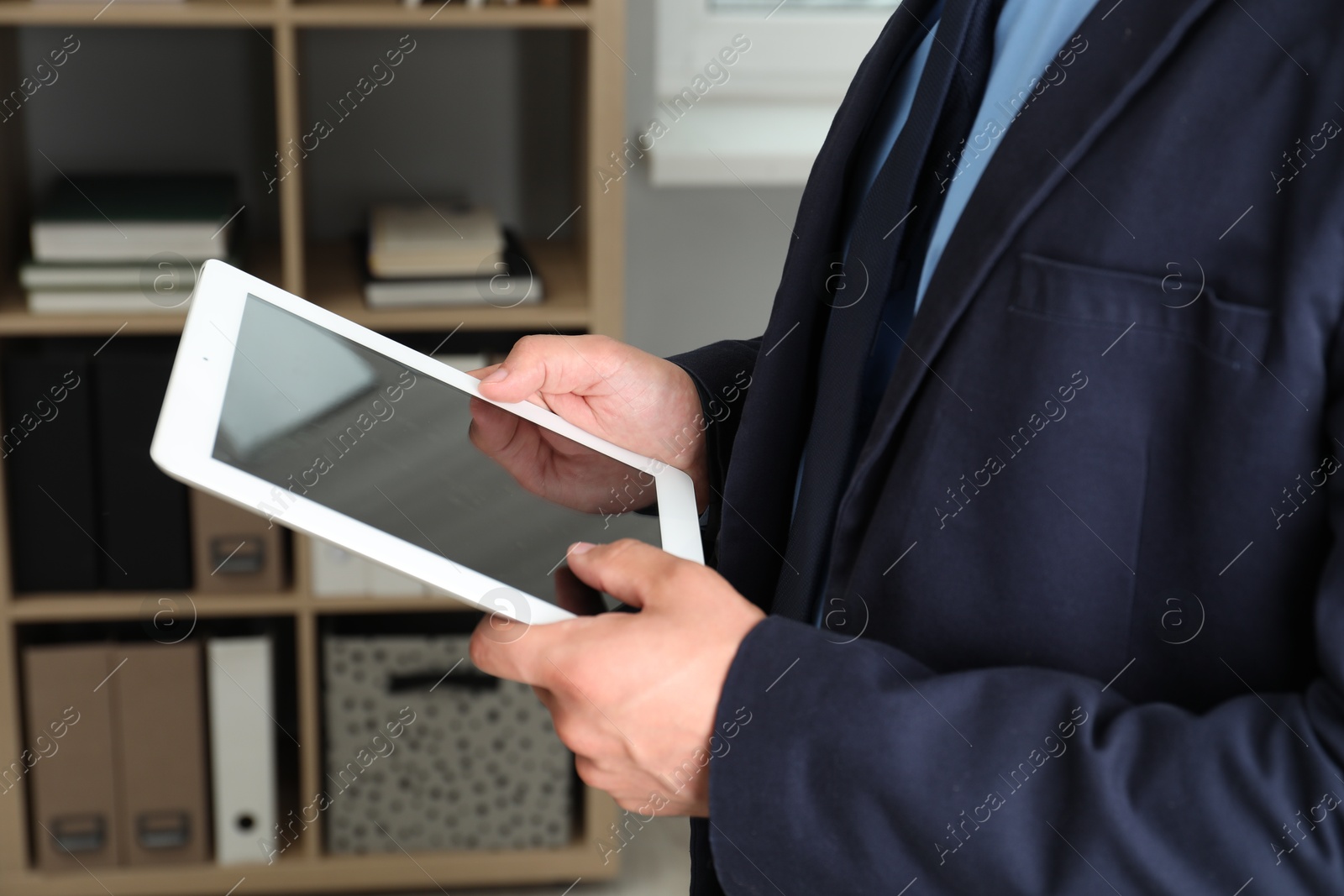 Photo of Businessman using tablet in office, closeup. Modern technology