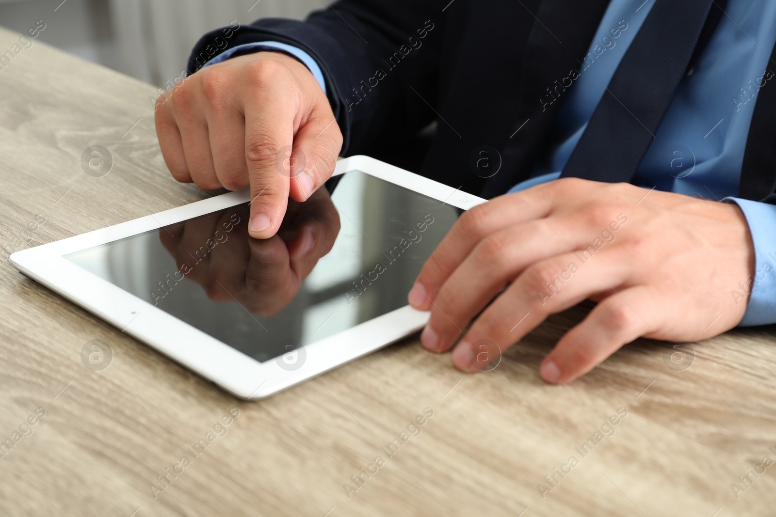 Photo of Businessman using tablet at wooden table, closeup. Modern technology