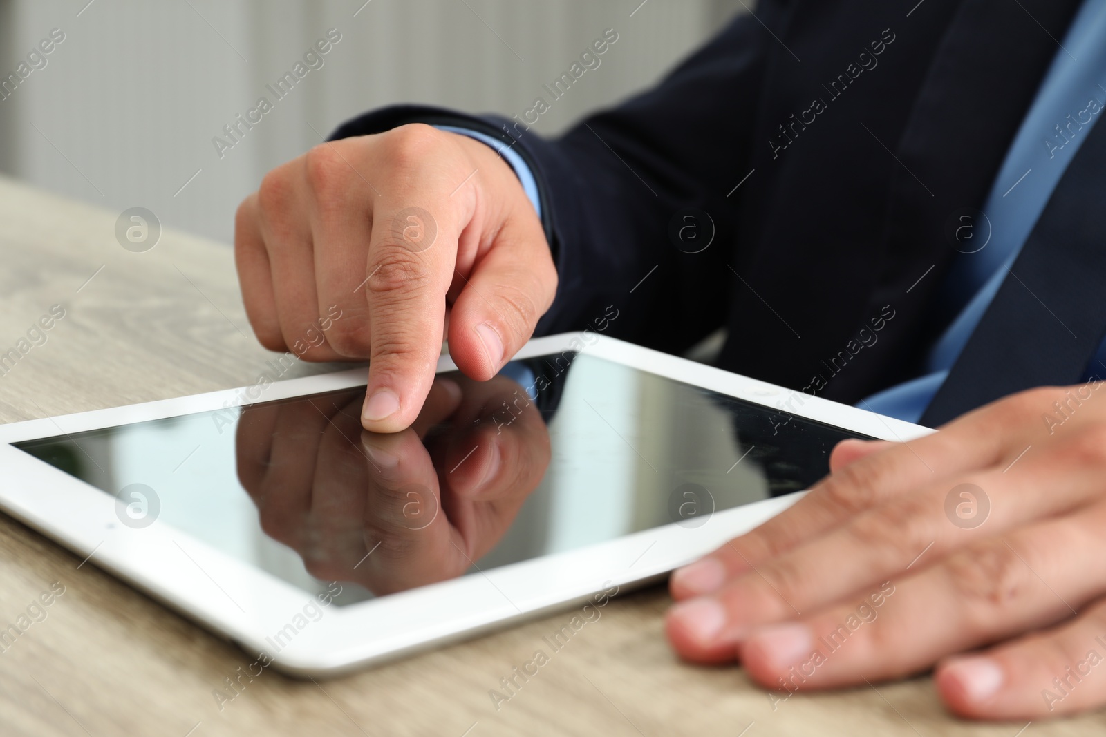 Photo of Businessman using tablet at wooden table, closeup. Modern technology