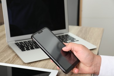 Photo of Businessman using smartphone at wooden table, closeup. Modern technology