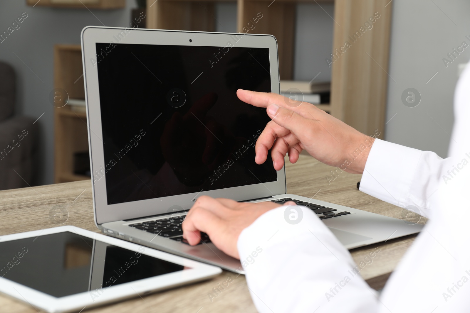 Photo of Businessman using laptop at wooden table, closeup. Modern technology