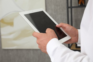 Photo of Businessman using tablet in office, closeup. Modern technology