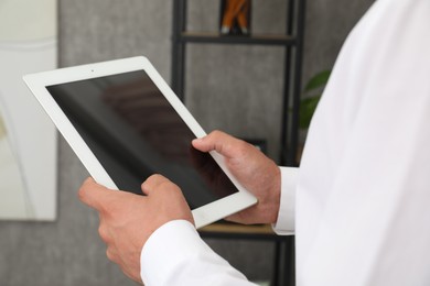 Photo of Businessman using tablet in office, closeup. Modern technology