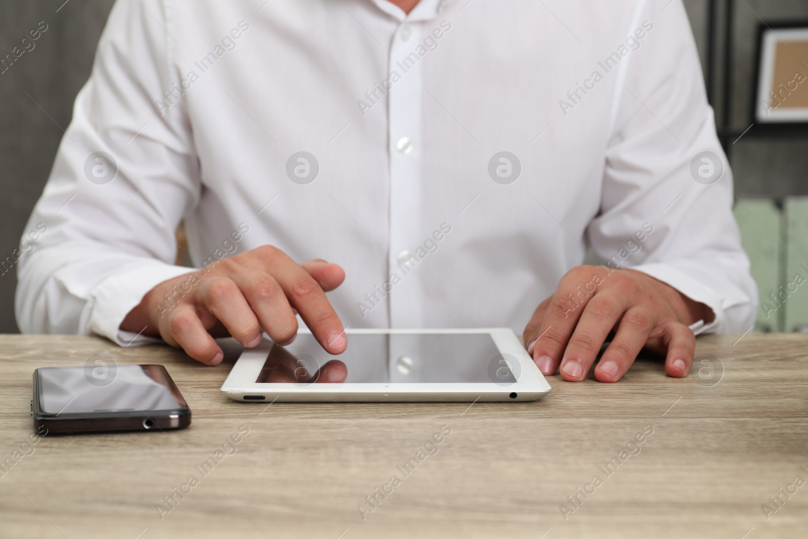 Photo of Businessman with tablet and smartphone at wooden table, closeup. Modern technology