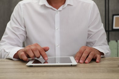 Photo of Businessman using tablet at wooden table, closeup. Modern technology