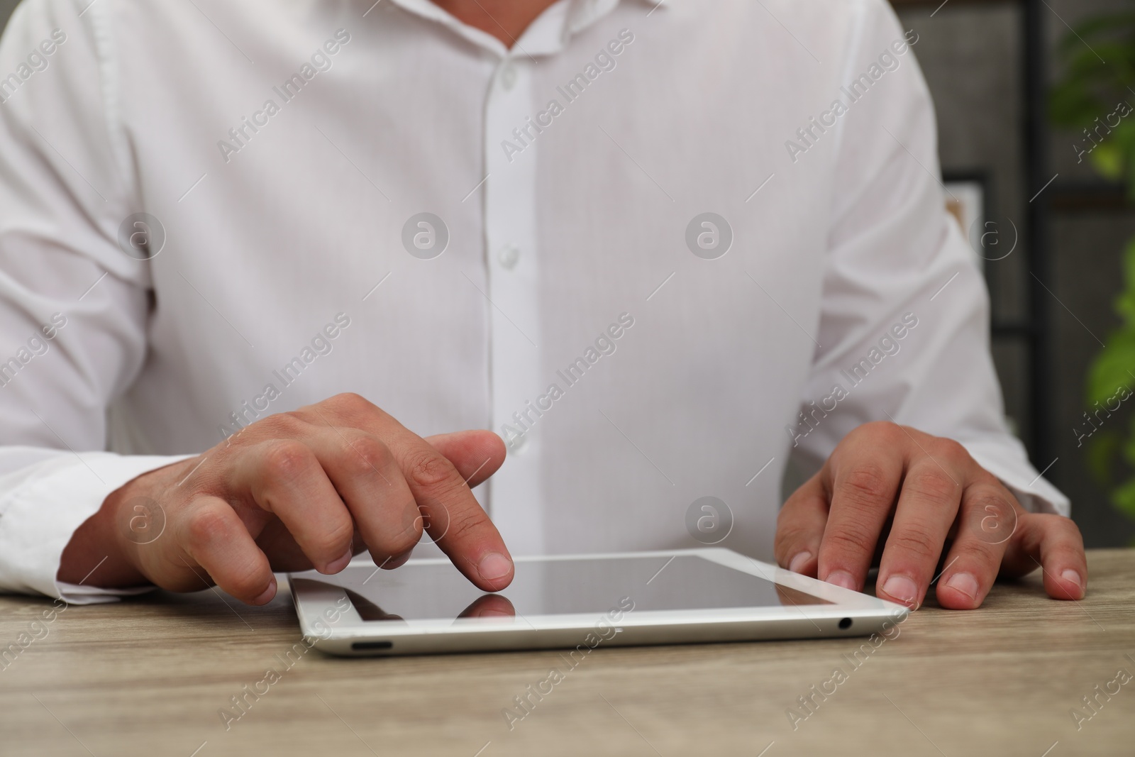 Photo of Businessman using tablet at wooden table, closeup. Modern technology